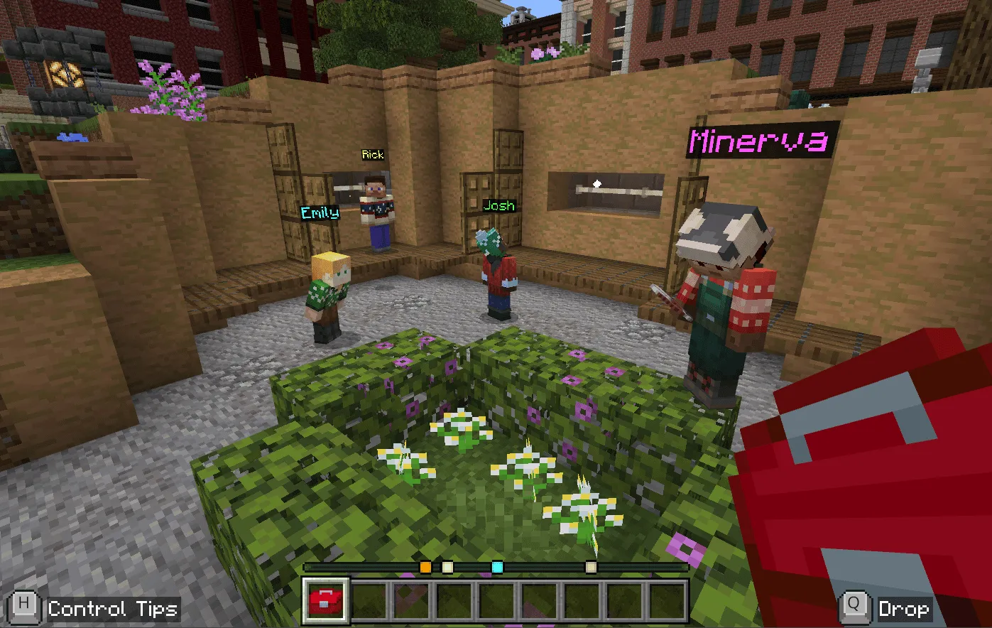 Students with custom nicknames and name colours above their heads in a Minecraft village